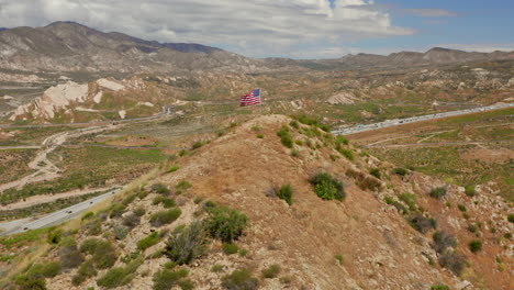 American-flag-on-top-of-a-hill-near-highway-15-near-Phelan,-California