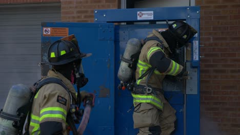 Feuerwehrmann-Bricht-Eine-Metalltür-In-Einem-Brennenden-Gebäude-Auf,-Um-Ein-Feuer-Zu-Bekämpfen