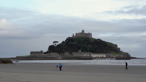 Niños-Jugando-Con-Una-Cometa-En-La-Playa-De-Marazion-En-Cornualles-Con-El-Castillo-Medieval-Inglés-Y-La-Iglesia-Del-Monte-De-San-Miguel-Detrás