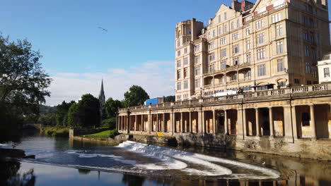 Statische-Aufnahme-Von-Pulteney-Wehr-Und-Dem-Empire-Hotel-In-Bath,-Somerset-An-Einem-Schönen-Sommermorgen-Mit-Blauem-Himmel-Und-Vögeln,-Die-In-Den-Rahmen-Fliegen