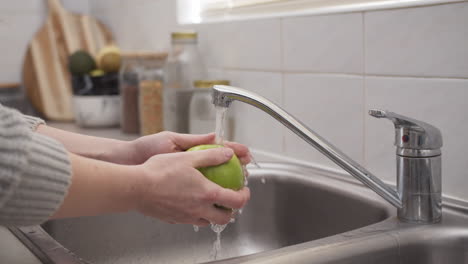 Weibliche-Hände,-Die-Einen-Apfel-In-Der-Küchenspüle-Waschen