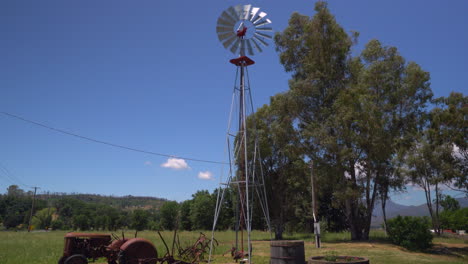 Blick-Auf-Eine-Rustikale-Windmühle-Neben-Einem-Oldtimer-Traktor-Und-Weinfässern-Auf-Einer-Farm-In-Nordkalifornien