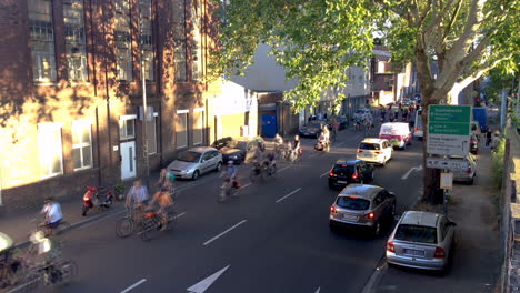 Un-Gran-Grupo-De-Ciclistas-Manifestantes-Dan-La-Vuelta-A-Una-Curva,-Seguidos-Por-Coches-De-Policía-En-La-Parte-De-Atrás