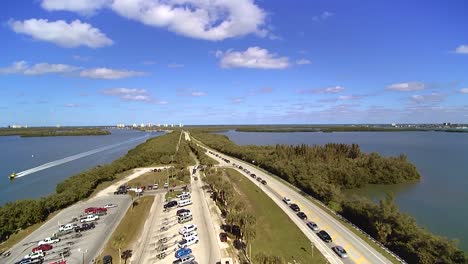 Luftaufnahme-Des-Nördlichen-Damms-Vor-Der-A1a-In-Ft-Pierce-Florida,-Autos,-Die-Die-A1a-Säumen,-Und-Ein-Gelbes-Seeschleppboot,-Das-Sich-Mit-Hoher-Geschwindigkeit-Auf-Der-Wasserstraße-Nach-Süden-Bewegt