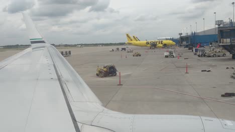 Looking-out-the-window-over-the-wing-of-an-airplane-as-it-rolls-back-to-prepare-for-take-off,-Detroit-Metro,-DTW,-cloudy