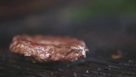 Slow-motion-close-up,-juicy-beef-burger-searing-on-a-blazing-outdoor-barbecue-grill