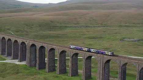 Aerial-Shot-of-a-Northern-Train-Crossing-Ribblehead-Viaduct-in-the-Yorkshire-Dales-from-Left-to-Right-with-a-Narrow-Crop