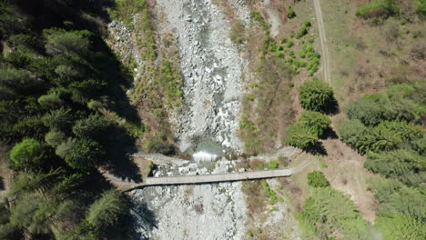 Top-down-aerial-view-of-a-mountain-river,-camera-moving-with-water-down-stream