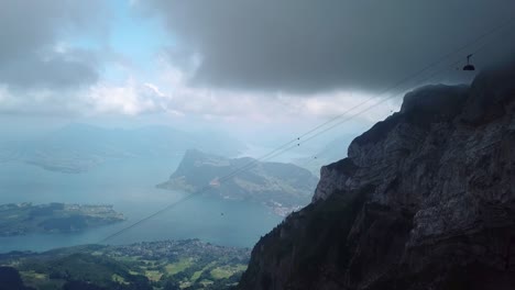 Luftaufnahme-Einer-Seilbahn-Mit-Einer-Gondel,-Die-Aus-Dem-Nebel-Den-Pilatus-Hinunterfährt