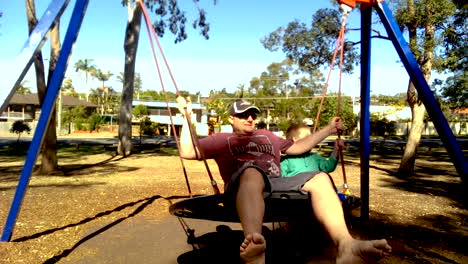 Man-swinging-on-large-rope-nest-swing-with-son
