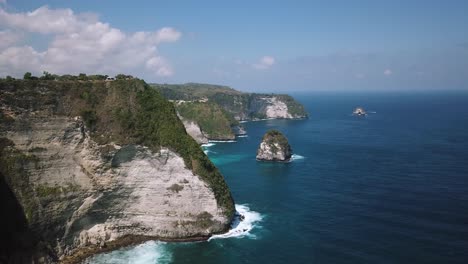 Rising-Drone-shot,-panning-down-and-revealing-the-beautiful-cliffs-near-KelingKing-Beach-on-the-island-of-Nusa-Penida,-Indonesia
