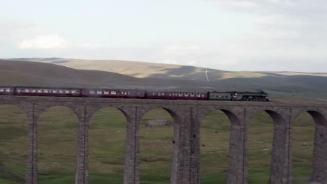 Toma-Aérea-Del-Tren-De-Vapor-Flying-Scotsman-60103-Que-Pasa-Sobre-El-Viaducto-Ribblehead-En-North-Yorkshire-Con-Un-Cultivo-Estrecho