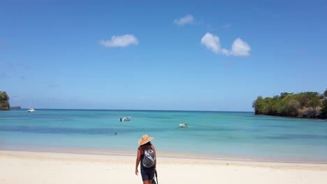 A-woman-walking-out-to-the-crystal-clear-waters-of-Mourne-Rouge-beach-located-on-the-Caribbean-island-of-Grenada