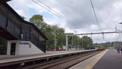 Toma-Panorámica-De-Un-Tren-Del-Norte-Que-Pasa-Por-Una-Estación-De-Cercanías-En-Las-Afueras-De-Leeds