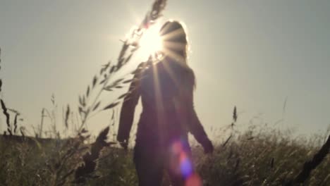 Woman-walking-through-farmers-field-at-sunset