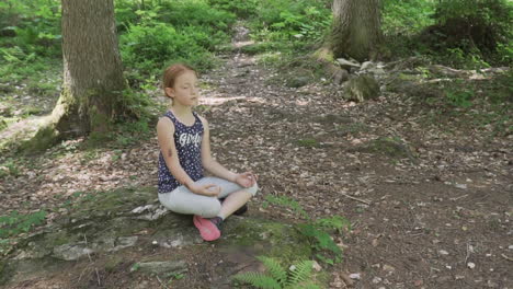 Kleines-Mädchen-Mit-Roten-Haaren-Meditiert-Im-Wald,-Zeitlupe
