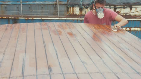 Youth-manually-sanding-boat-roof-planking
