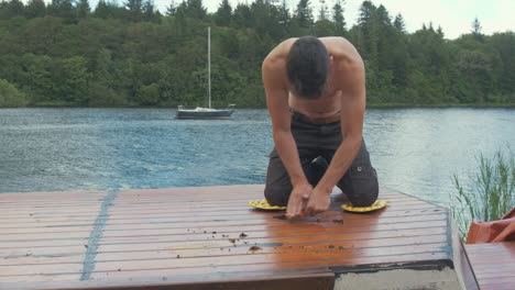 Topless-youth-scraps-mastic-sealant-off-boat-cabin-roof-planking