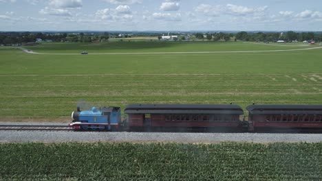 Luftaufnahme-Eines-Thomas-The-Tank-Engine-Mit-Passagierwagen,-Die-Entlang-Der-Amischen-Landschaft-Schnaufen