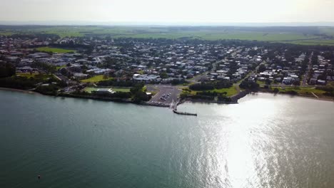 Aerial-footage-into-the-sun-flying-towards-the-town-of-Inverloch,-Victoria,-Australia