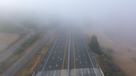 Aerial-view-of-traffic-headed-over-a-bridge-into-thick-fog-on-major-freeway