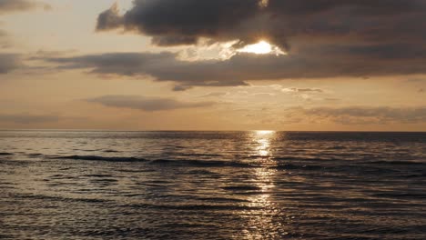 Sunset-over-sea,-ocean-water-with-calm-waves-and-beautiful-light,-steady-shot