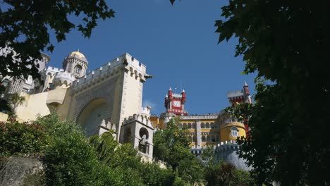 Hermosa-Vista-A-Través-De-Los-árboles-A-La-Torre-Del-Reloj-Del-Colorido-Palacio-Pena-En-Un-Día-Claro-En-Sintra,-Portugal