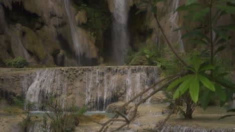 Zeitlupenclip-Auf-Einem-Kleinen-Wasserfall-Mit-Grünen-Blättern-Vor-Der-Kamera