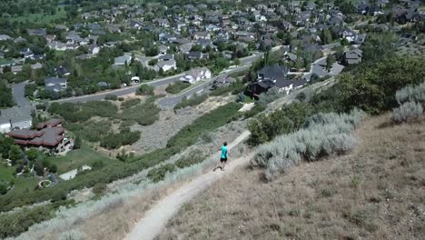 Drone-Shot-following-an-active-man-running-on-the-outdoor-mountain-trails-above-Draper-City,-Utah