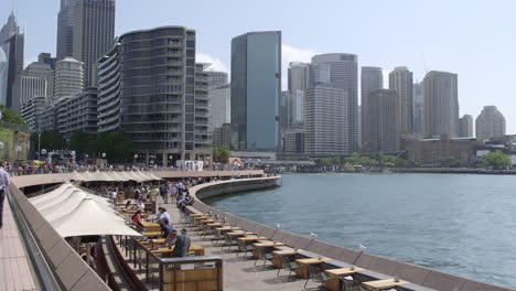 Sydney-skyline-in-the-background,-people-enjoying-outdoor-dining-by-the-circular-quay