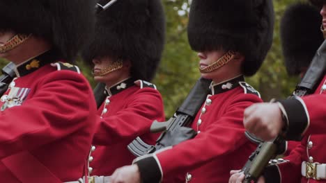 London-Queen's-Guard,-contingents-of-infantry-and-cavalry-soldiers-charged-with-guarding-official-royal-residences-in-United-Kingdom-marching-in-rows,-handheld-close-up-slow-motion
