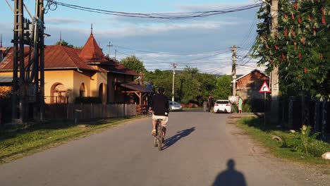 Moreni,-Rumania---13-De-Julio-De-2020:-Hombre-Con-Bicicleta-Negra-En-Una-Carretera-Rural-Al-Atardecer,-Cámara-Lenta