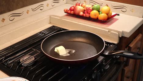 Woman-putting-butter-pats-into-a-hot-skillet-in-a-tiny-home-kitchen