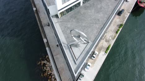 Large-Mercedes-Benz-sign-spinning-on-top-of-Hong-Kong-Mercedes-Benz-main-showroom-in-Chai-Wan-area,-Aerial-view