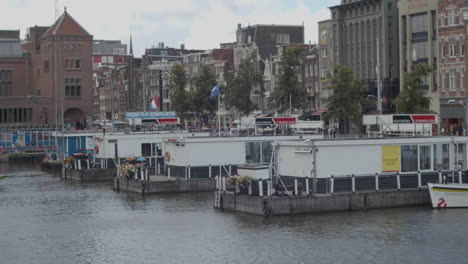 Panning-over-Sightseeing-tour-boat-docked-in-city-centre-of-Amsterdam