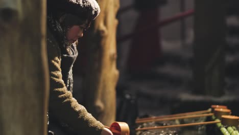 Japanese-Woman-Washing-Her-Hands-At-The-Temizuya-Washing-Basin-At-The-Kifune-Jinja-Shrine-In-Kyoto,-Japan-At-Night