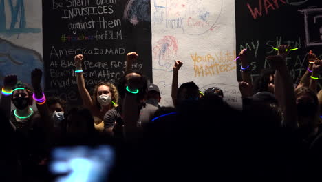 Multitud-De-Manifestantes-Levantando-Puños-Mientras-Sostienen-Coloridos-Palillos-Luminosos-En-Tiza-La-Protesta-Del-Bloque-Por-La-Noche