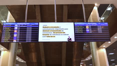 Tablero-De-Información-Del-Horario-De-Salida-En-El-Aeropuerto-De-La-Ciudad-De-Santos-Dumont-De-Vuelos-Nacionales-Con-Instrucciones-Sobre-El-Brote-Del-Virus-Covid-19-Utilizando-Principalmente-Una-Máscara-Facial-En-Todo-Momento