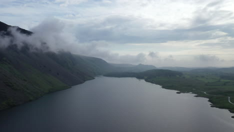 Aerial-shot-over-a-lake-positioned-below-a-mountain-in-the-English-Lake-District