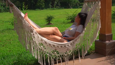 Young-woman-swings-on-hammock-while-looking-surrounding-countryside