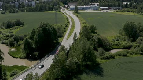 Aerial-pan-up-of-a-group-of-people-riding-on-bikes-near-a-road-in-the-countryside-of-Kerava,-Finland