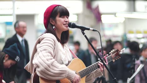 Joven-Japonesa,-Guitarrista-Y-Cantautora-Tocando-Alegremente-En-La-Calle-Kawaramachi-En-Kyoto,-Japón