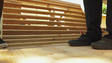 Man-uses-a-power-drill-to-insert-a-screw-into-a-sheet-of-plywood-while-making-a-skateboard-ramp