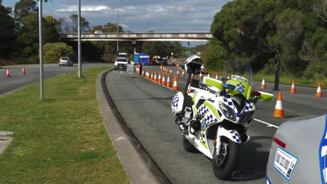 Polizeimotorrad-Geparkt-Hinter-Dem-Polizeiauto---Polizeikontrollpunkt-An-Der-Nsw---Qld-staatsgrenze---Pandemie-coronavirus-beschränkungen-In-Australien