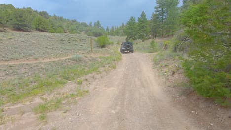 Punto-De-Vista-Siguiendo-Un-Jeep-En-Un-Camino-Todoterreno-De-Tierra-A-Través-De-Las-Montañas-De-Colorado