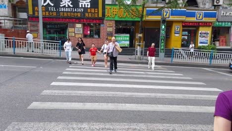 Slow-motion-clip-of-men,-women-and-children-crossing-the-busy-street-on-zebra-crossing-in-chinese-town-Chongqing,-China