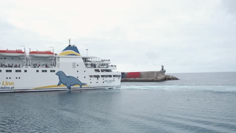 Large-white-passenger-boat-cruises-and-enters-Porto-Santo-port-waters-by-cement-pier-in-harbor,-Portugal,-static-profile