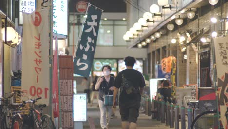 Gente-Caminando-Junto-A-Los-Restaurantes-Y-Bares-Por-La-Noche-En-Kamata,-Tokio,-Japón