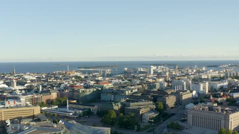 Slow-aerial-shot-high-above-the-buildings-of-Helsinki,-Finland-with-ocean-in-distance