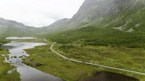 Car-Driving-On-The-Narrow-Road-By-The-Lush-Mountain-In-Hydalen,-Hemsedal-On-A-Foggy-Day---aerial-panning-shot
